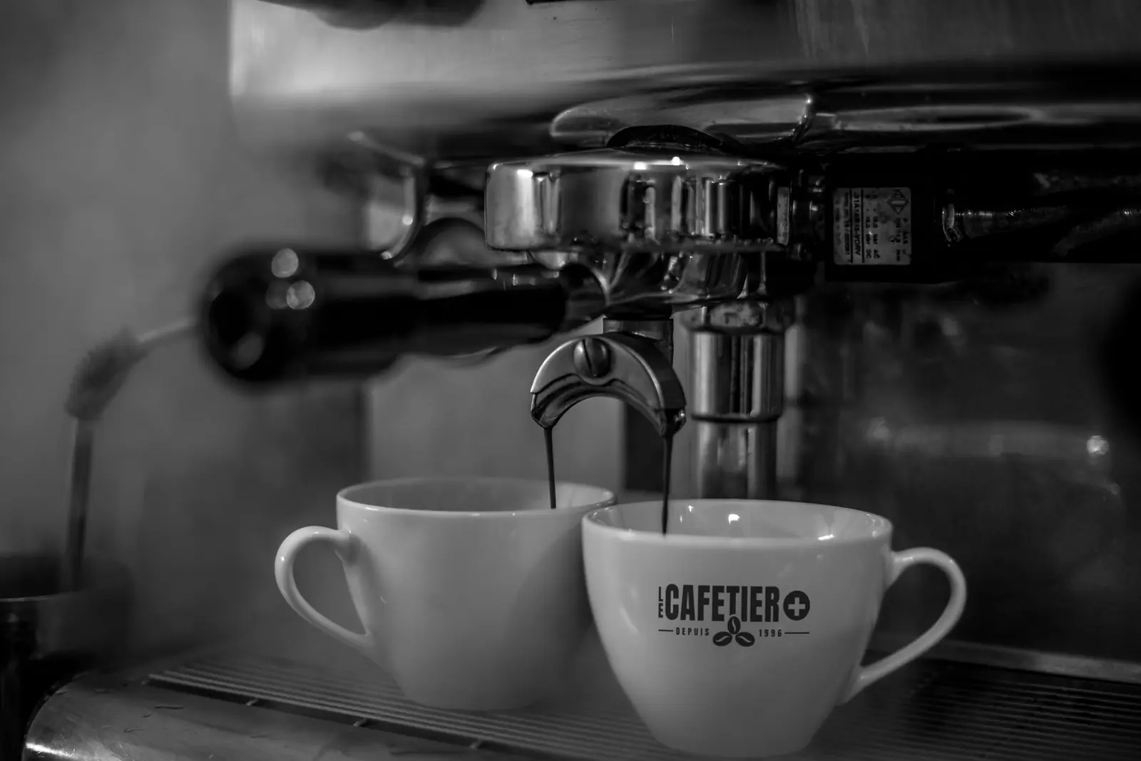 Deux tasses sous une machine à espresso, l’une au logo du Cafetier Plus